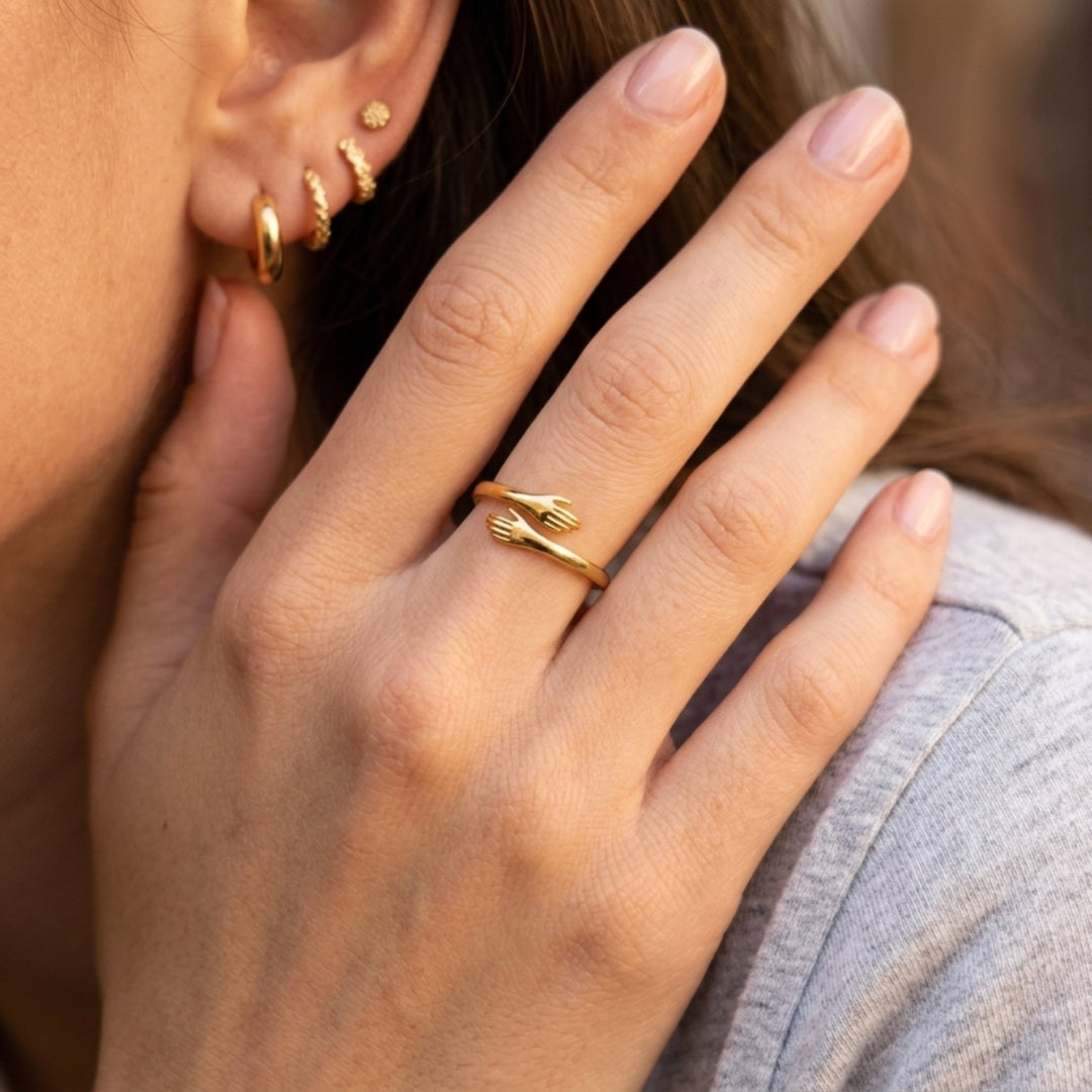 Femme portant la bague câlin dorée, main posée près du cou