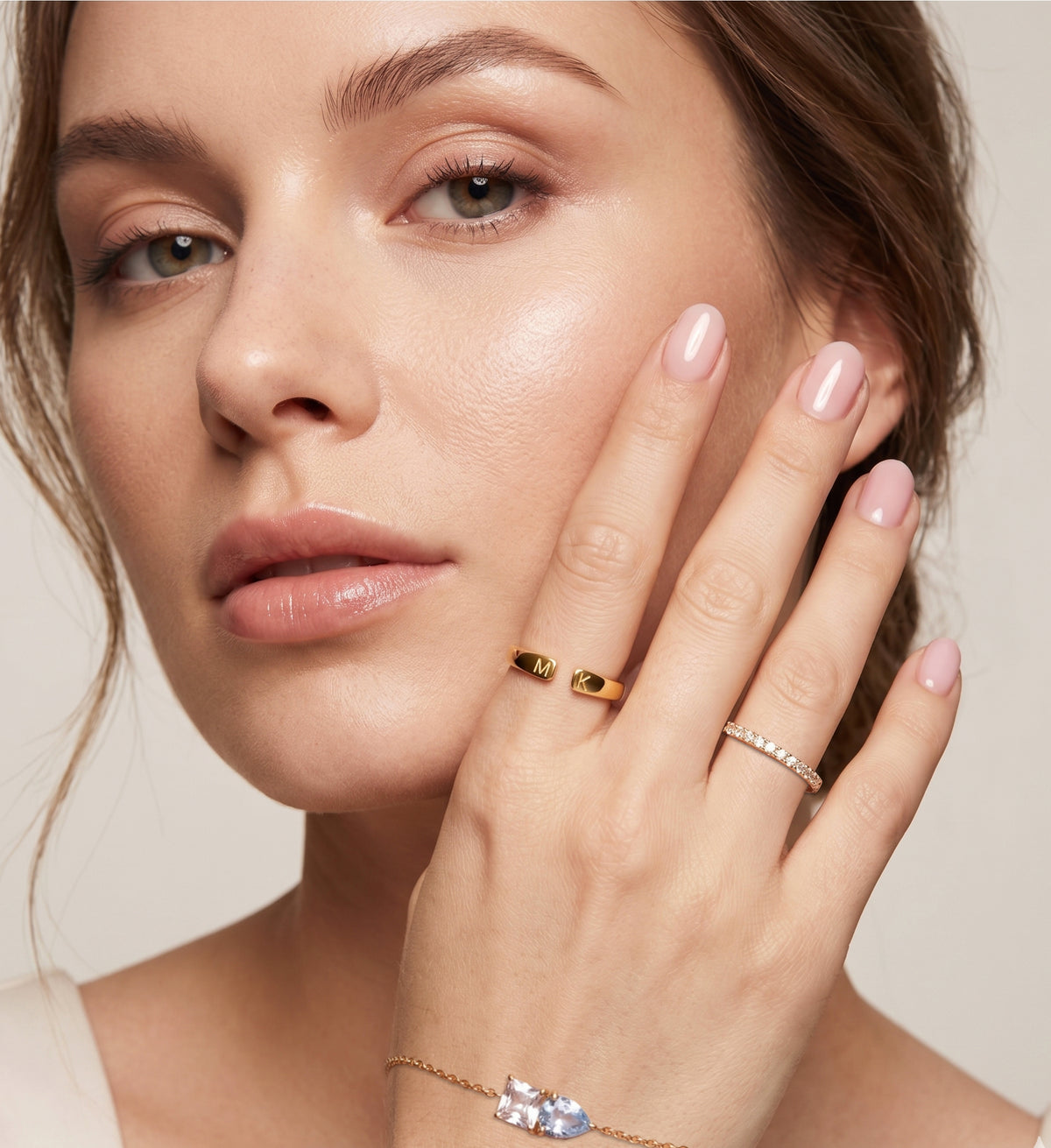 Femme portant une bague avec initiale dorée, main posée près du visage