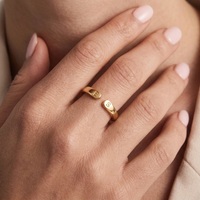 Bague initiale dorée portée, initiales gravées visibles sur le dessus de l'anneau