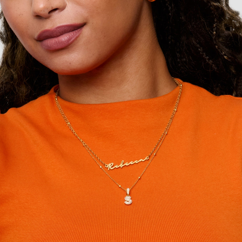 Collier prénom or porté sur peau mate, contraste doux avec le métal Image