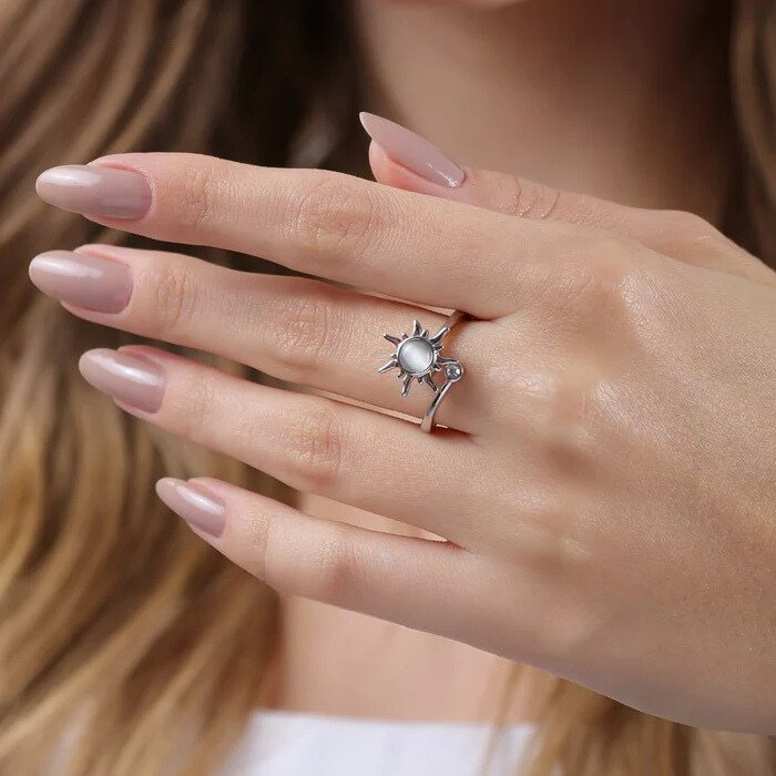 Gros plan sur la bague soleil anti-stress Akira argentée portée au doigt