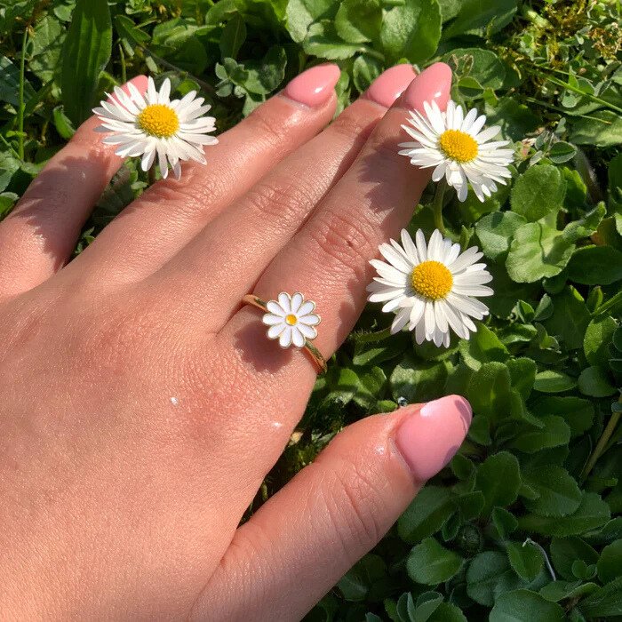Bague fleur anti-stress Marguerite portée au milieu de vraies marguerites
