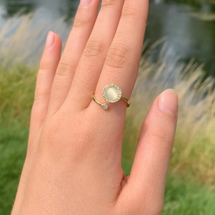 Main portant la bague anti-stress Œil de chat dorée en extérieur Image
