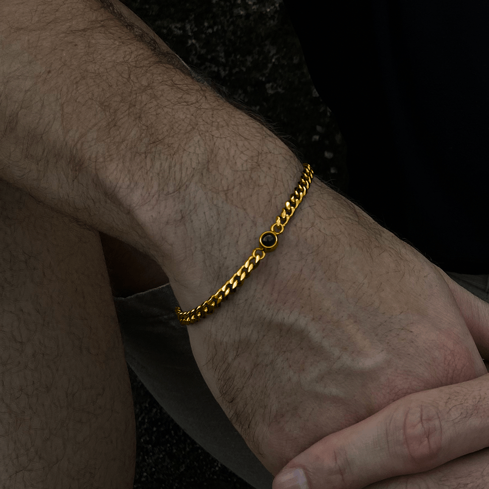 Bracelet chaîne cubaine dorée à photo cachée porté au poignet d'un homme