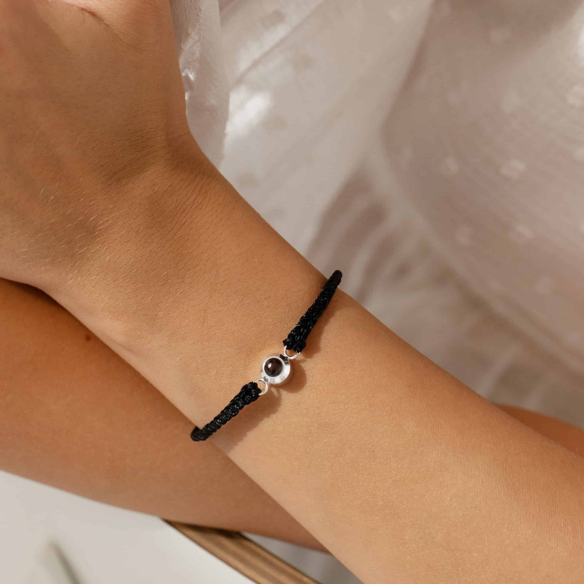 Bracelet tressé noir à projection photo porté au poignet d'une femme