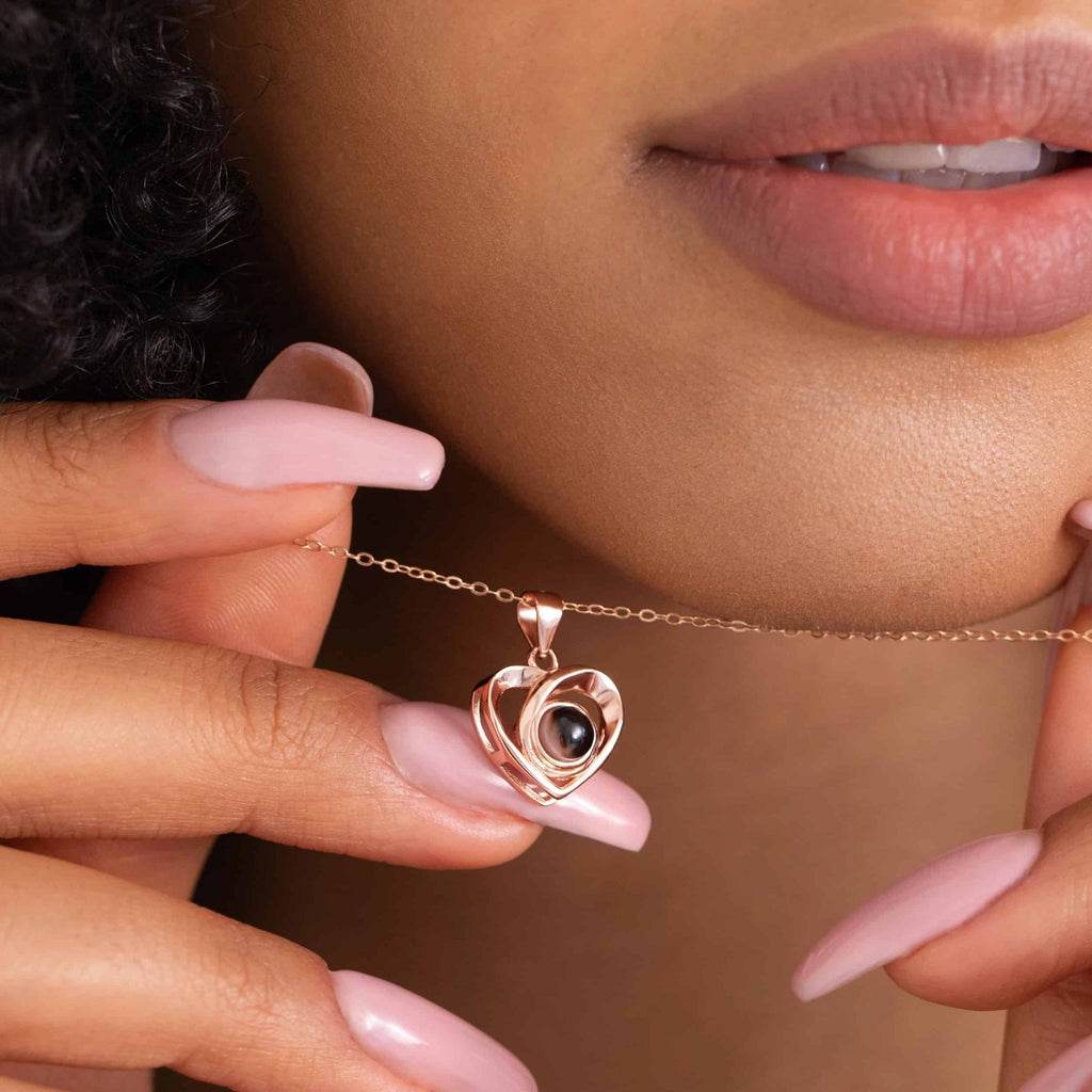 Pendentif cœur photo à projection or rose tenu entre les doigts, bijou personnalisé