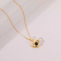 Pendentif cœur doré à projection photo posé sur fond rosé, collier personnalisé