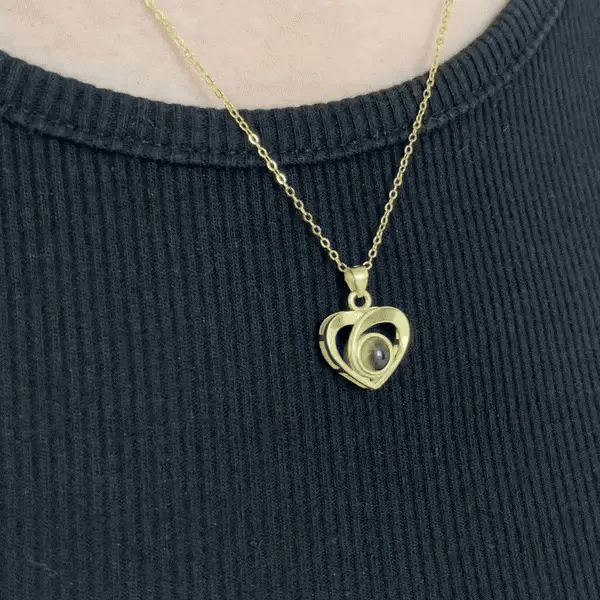 Pendentif cœur photo à projection doré porté sur pull noir