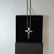 Pendentif croix photo à projection pour homme posé sur sa boîte noire