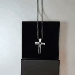 Pendentif croix photo à projection pour homme posé sur sa boîte noire