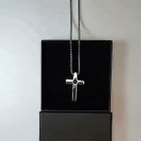 Pendentif croix photo à projection pour homme posé sur sa boîte noire