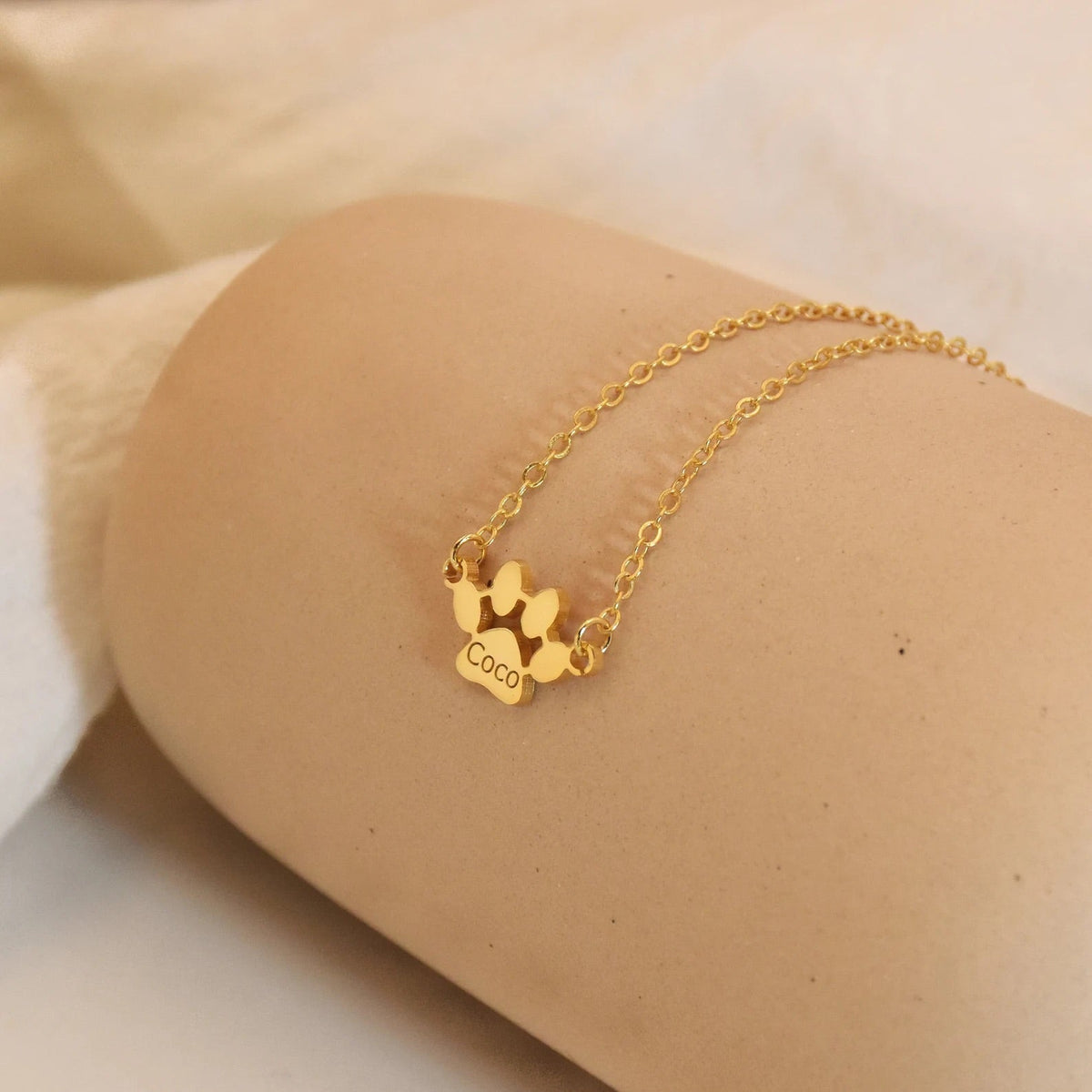 Gros plan pendentif patte chien doré gravé prénom animal - bijou personnalisé cadeau Petale Paris